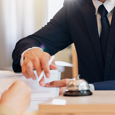 Hotel,,Info,And,Woman,At,Desk,With,Man,,Check,In